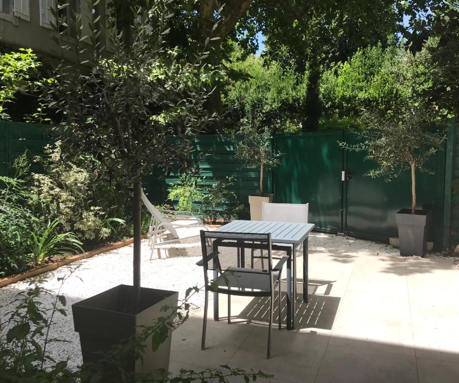 uma mesa e cadeiras sentadas ao lado de uma árvore em Les Ecuries - Triplex contemporain avec jardin em Avignon