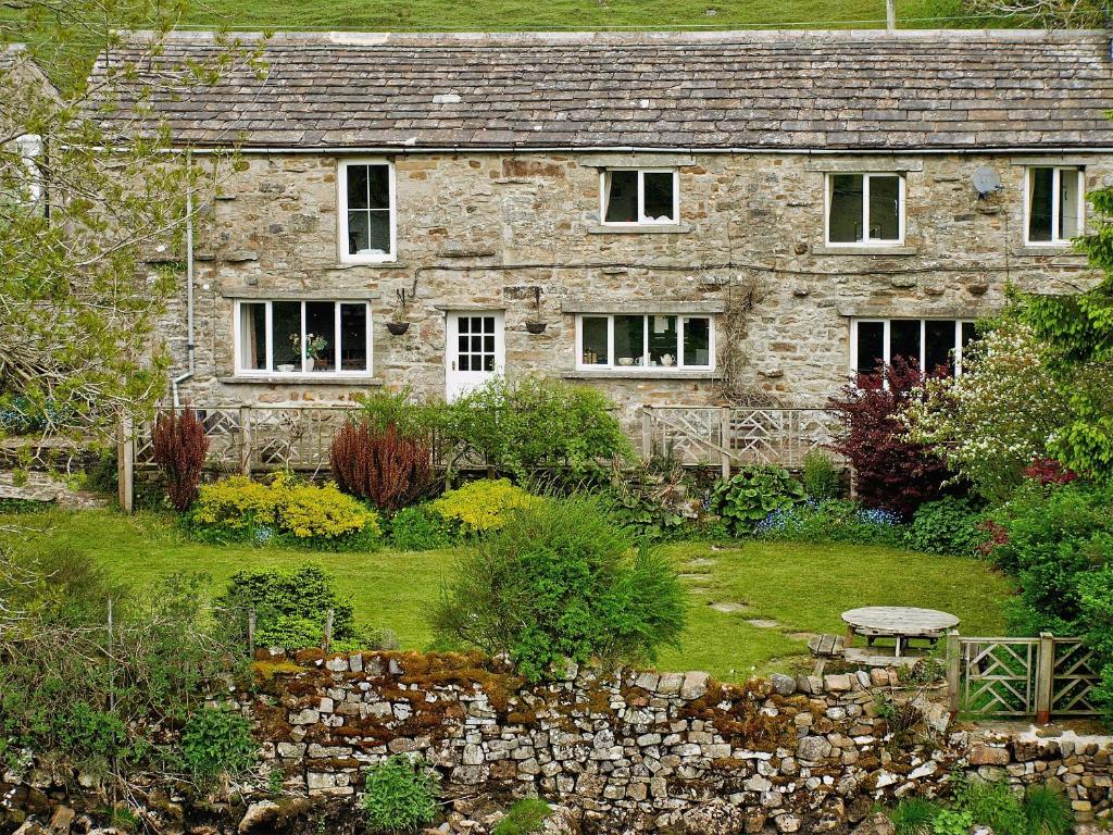 a stone house with a garden in front of it at Elm Cottage in Beckermonds