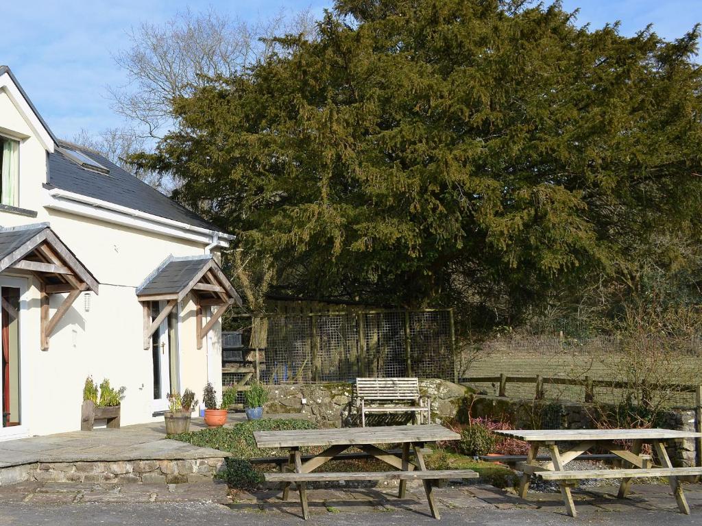 Hoel-galed的住宿－Ty Newydd Cottage，房屋前设有两张木制野餐桌