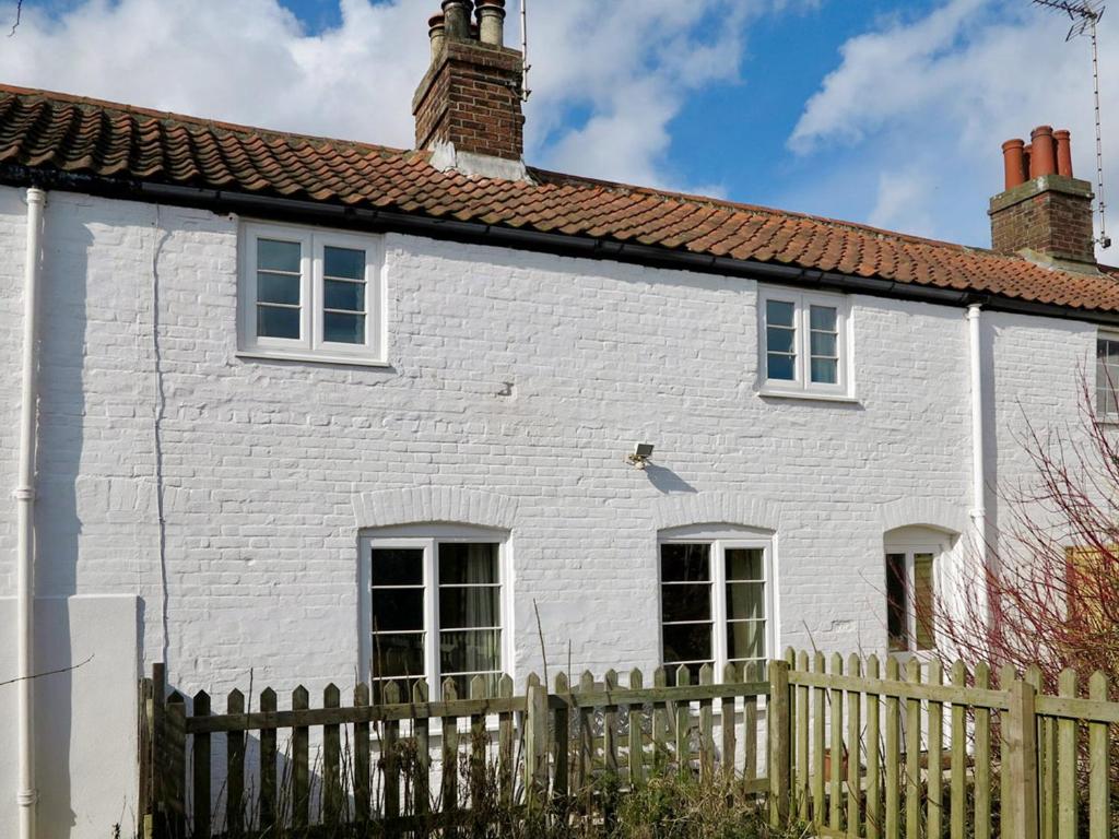 a white house with a fence in front of it at Jennys Cottage 27553 in Mundesley