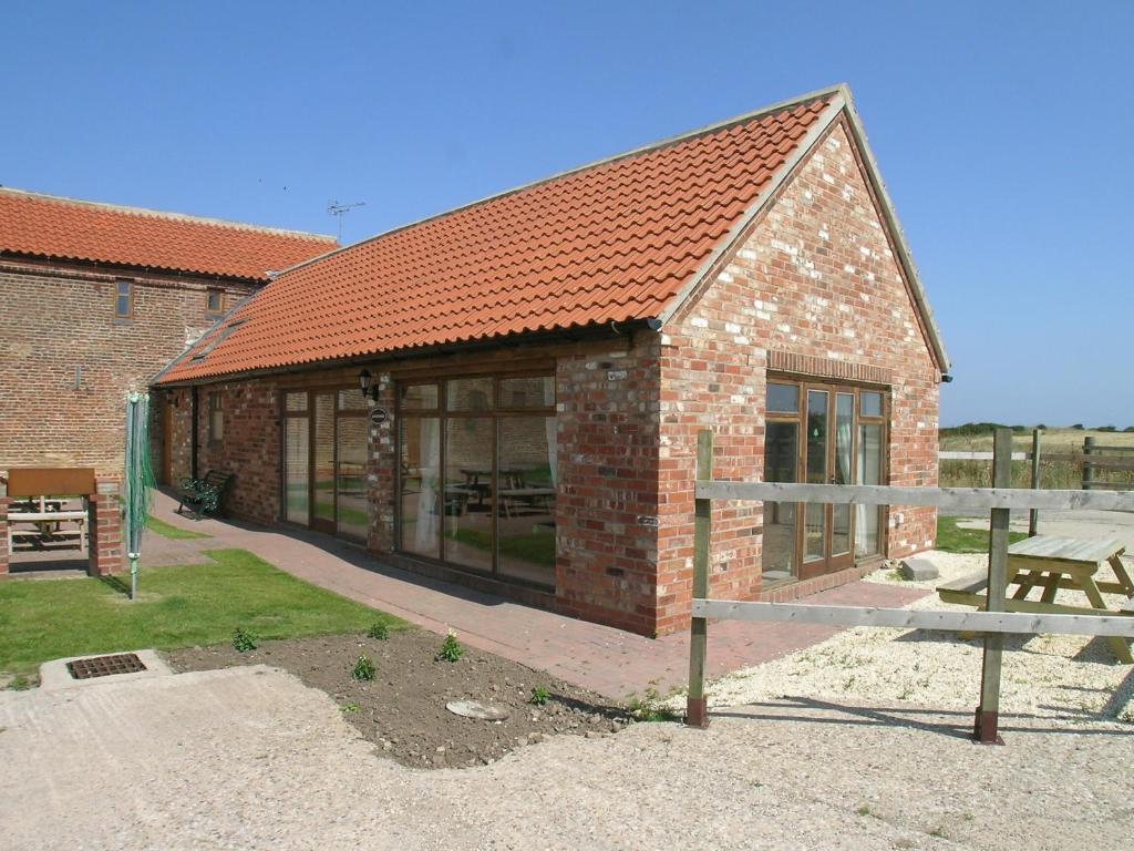 a brick building with a bench in front of it at Kingfisher Cottage - 25114 in Flamborough