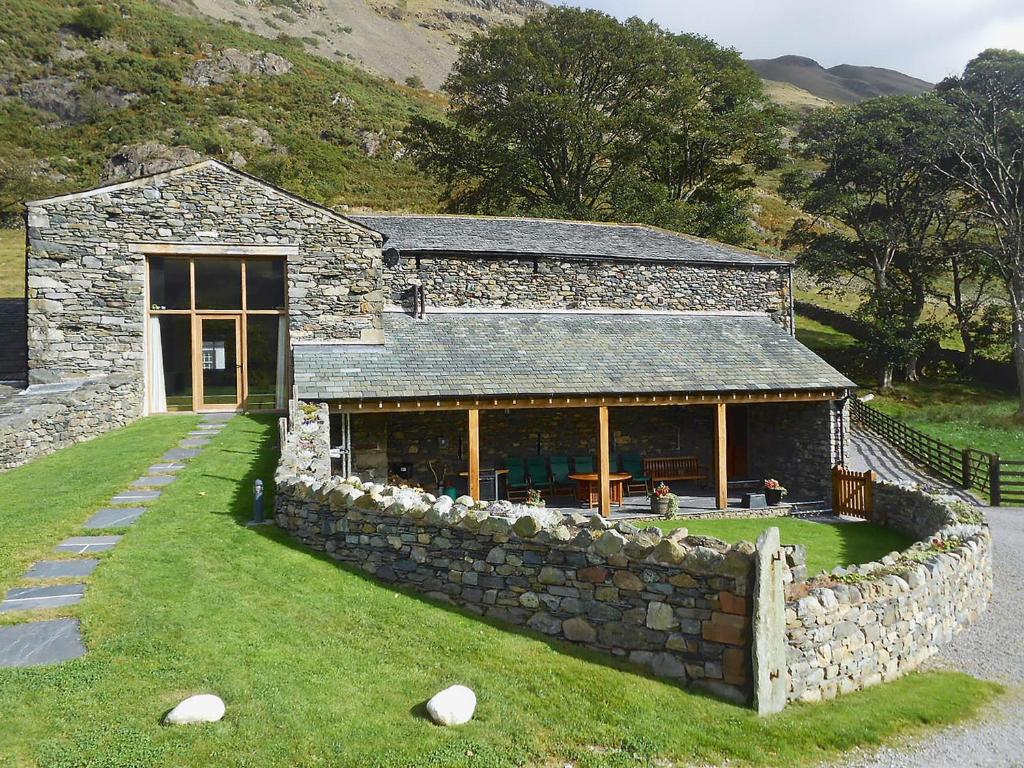 una casa de piedra con una pared de piedra delante de ella en Bram Crag Barn en Legburthwaite