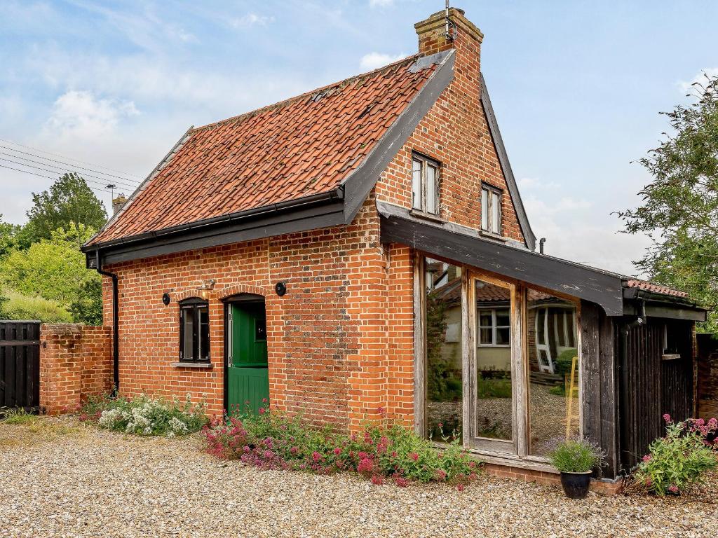 una casa in mattoni rossi con una porta verde di The Old Bike Shop a Brockdish