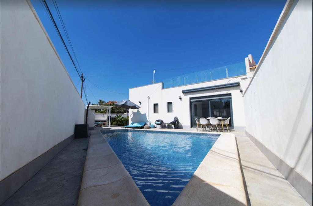 a swimming pool in front of a building with a house at Arenas house in Torrevieja