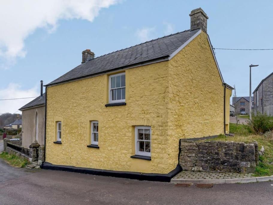 a yellow house with a black roof on a street at Yellow Welsh Cottage-Coastal Retreat Village View in Bridgend