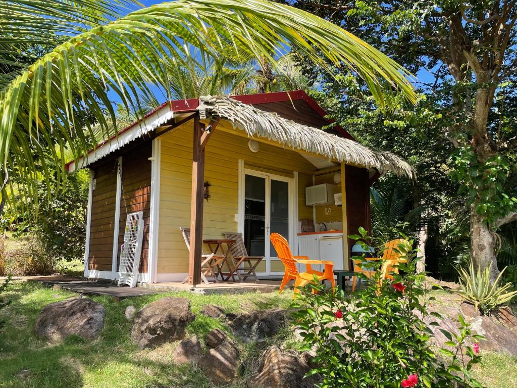 une petite maison jaune avec des chaises orange devant elle dans l'établissement Résidence COCO D'ILES, Gite TI BAMBOU, à Terre-de-Bas