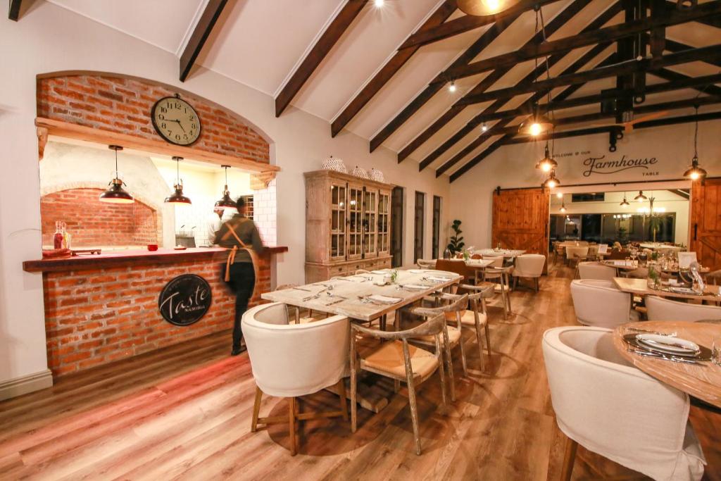 a restaurant with tables and chairs and a clock on the wall at Otjiwa Safari Lodge in Otjiwarongo