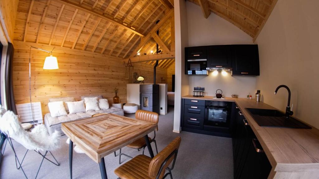 uma cozinha e uma sala de estar com um sofá e uma mesa em Les pavillons de La Libellule em Beauraing