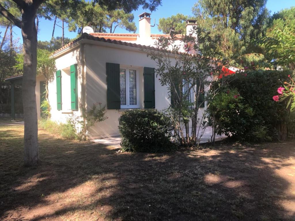une petite maison blanche avec des volets verts et un arbre dans l'établissement La maison des Epinouses, à Chaucre
