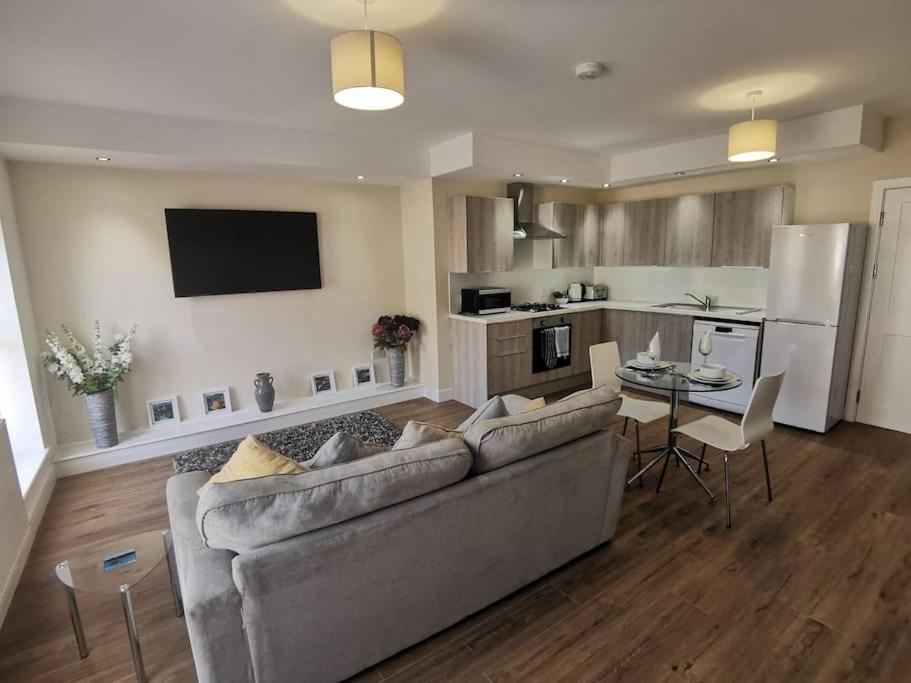 een woonkamer met een bank en een tafel en een keuken bij Griffin Apartments in Nottage