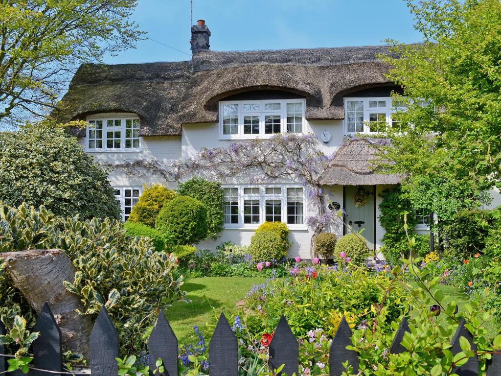 an old house with a thatched roof and a garden at Starboard Cottage in Winterton-on-Sea