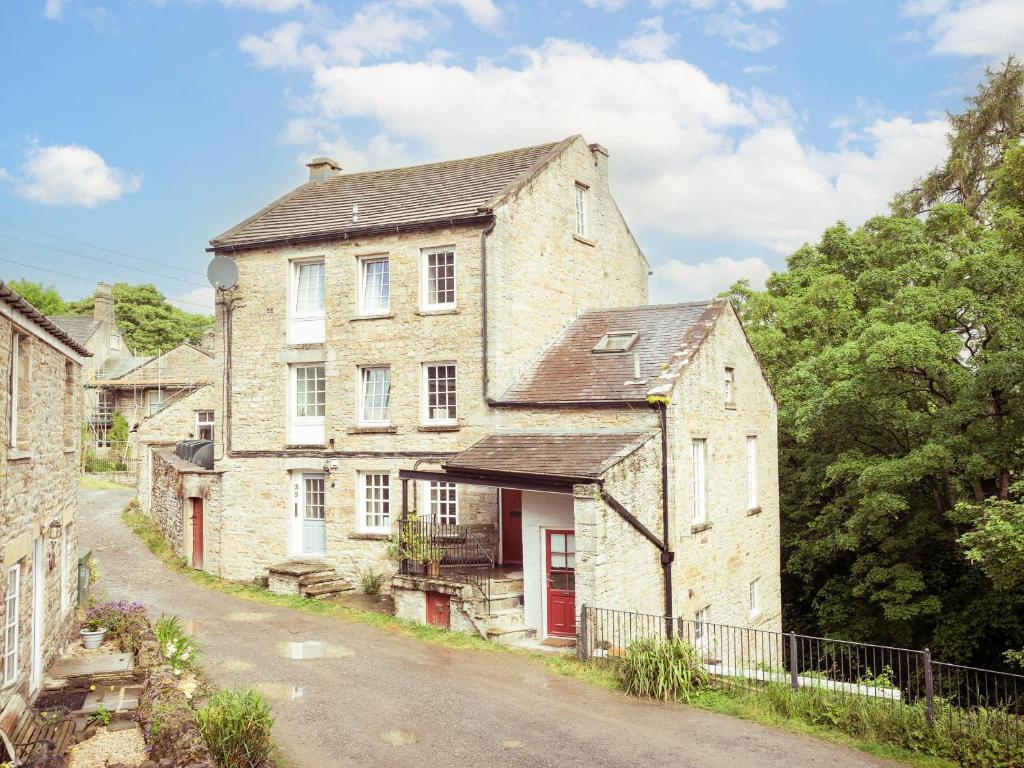 an old stone house on the side of a road at Waters Edge Apartment The Mill in West Burton