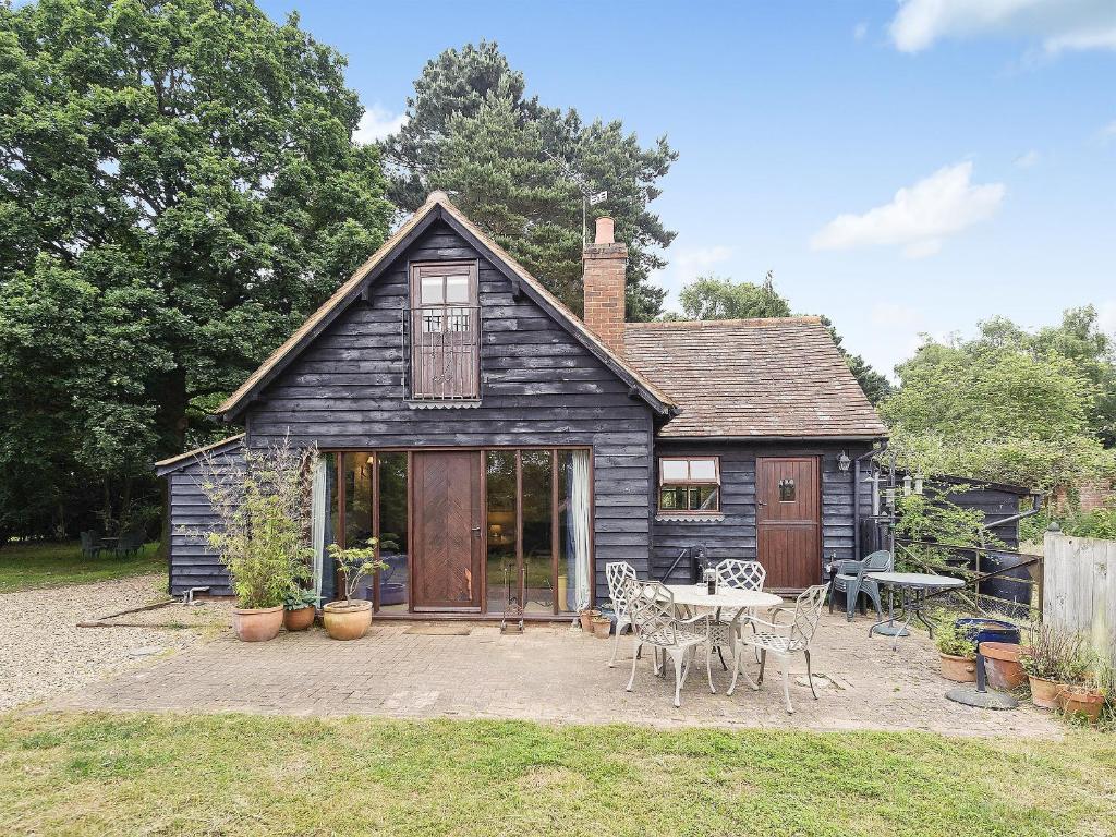 Cette petite maison dispose d'une terrasse et d'une table. dans l'établissement Coach House, à Melton