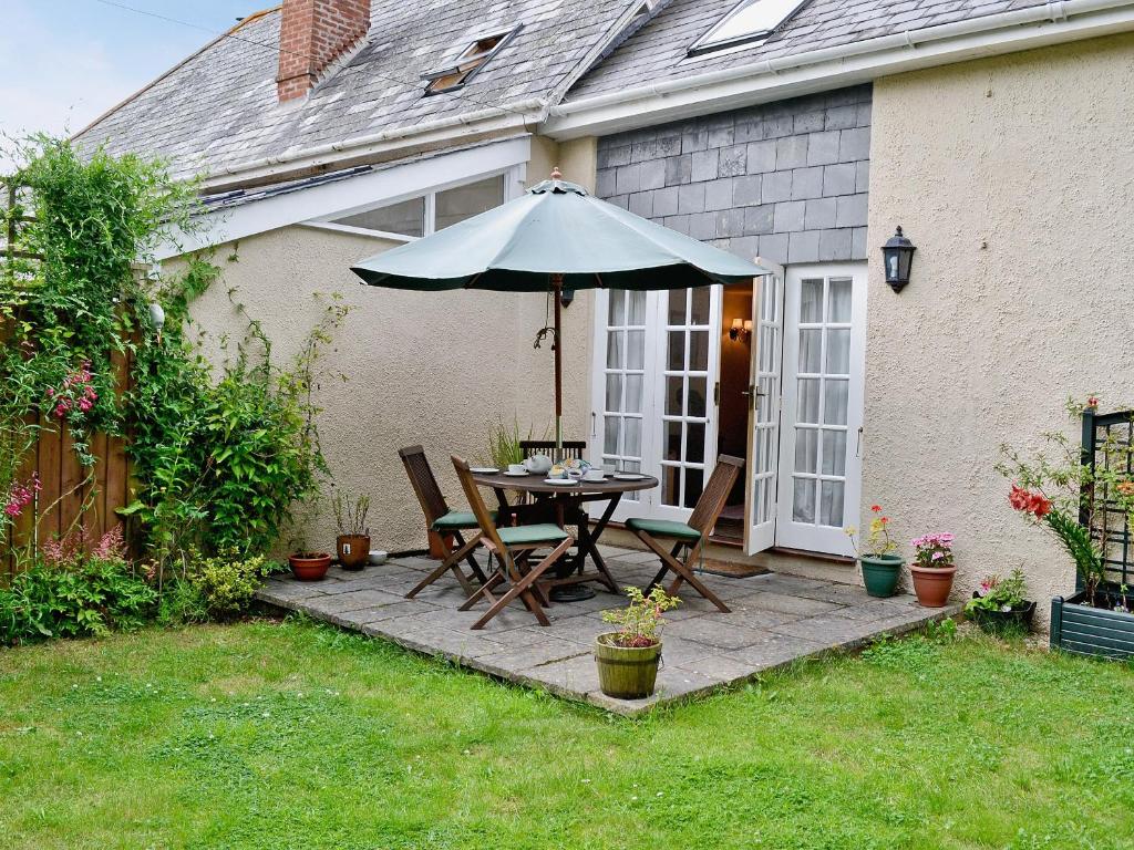 a patio with a table and an umbrella at Nightingales in Kentisbeare