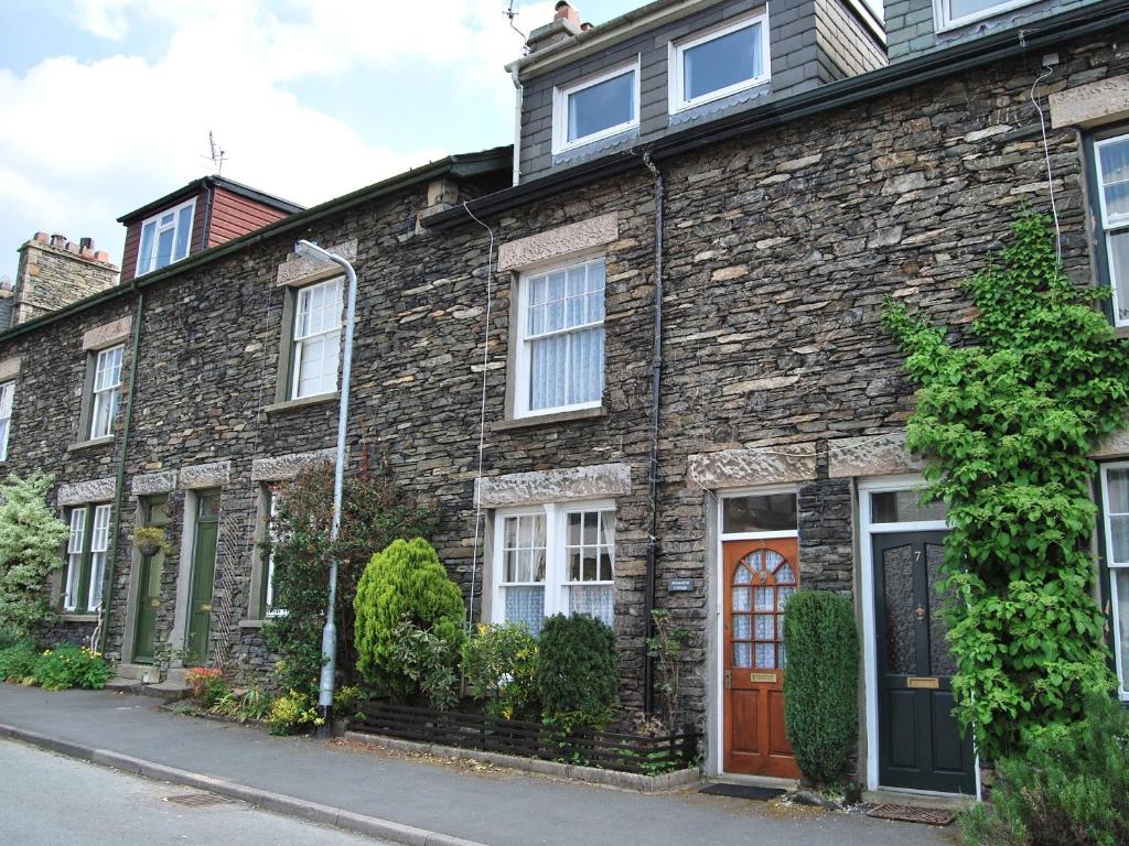 a brick house with a wooden door on a street at Alexandra Cottage in Windermere