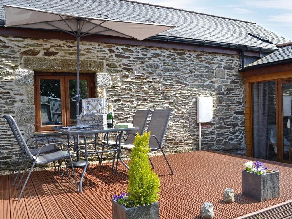 a patio with a table and chairs and an umbrella at Black Thorn Cottage in Falmouth