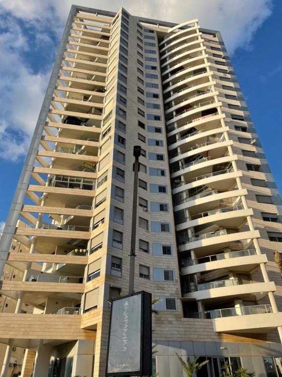 a tall apartment building with a sign in front of it at ISRALUX APARTMENTS in Bat Yam