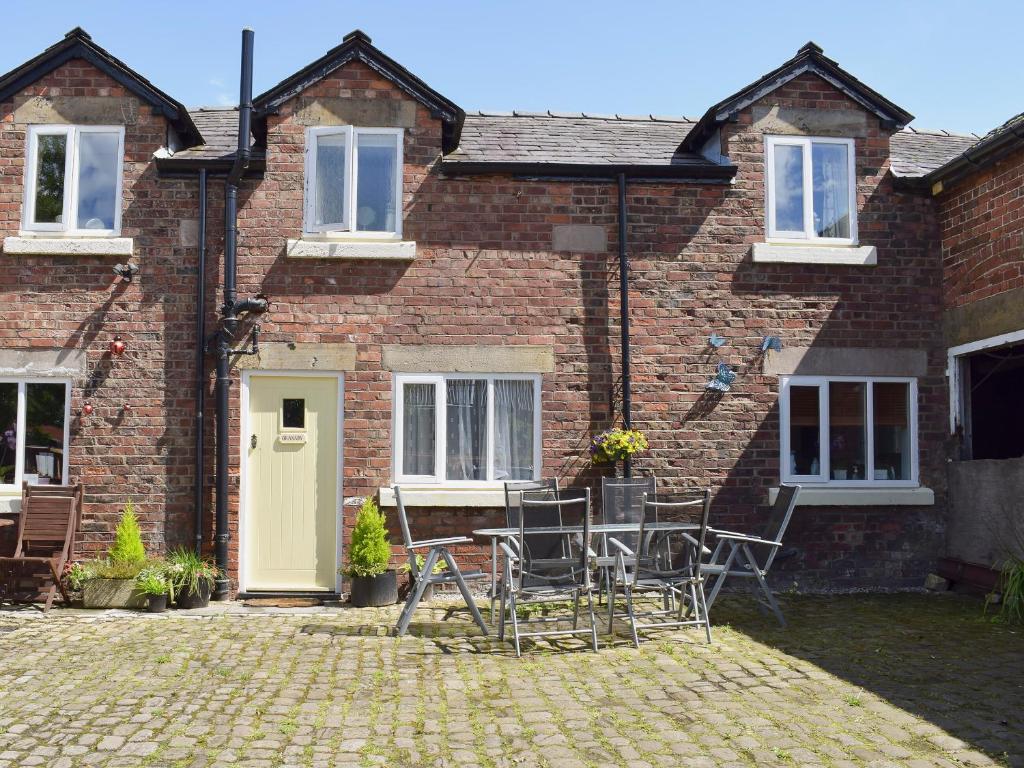 a brick house with chairs and a table in front of it at The Granary in Burscough