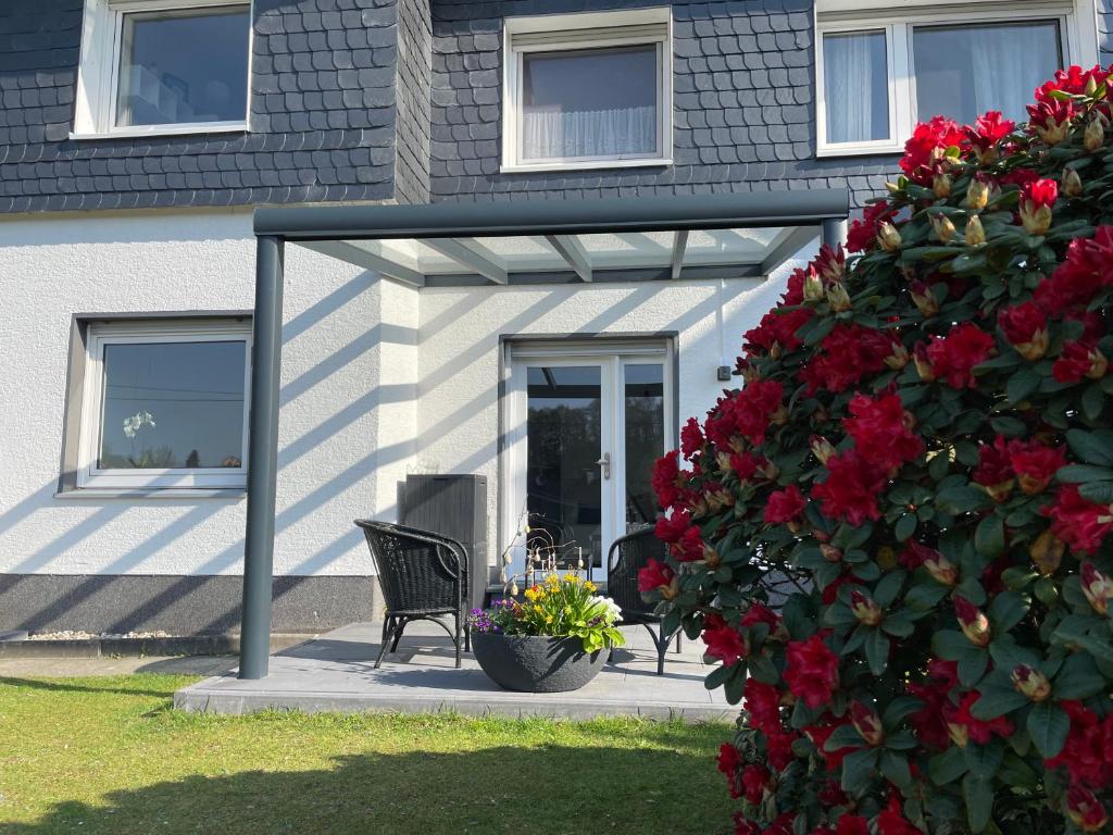 a pergola on a house with a bench and red flowers at Ferienwohnung Jakob in Lindlar