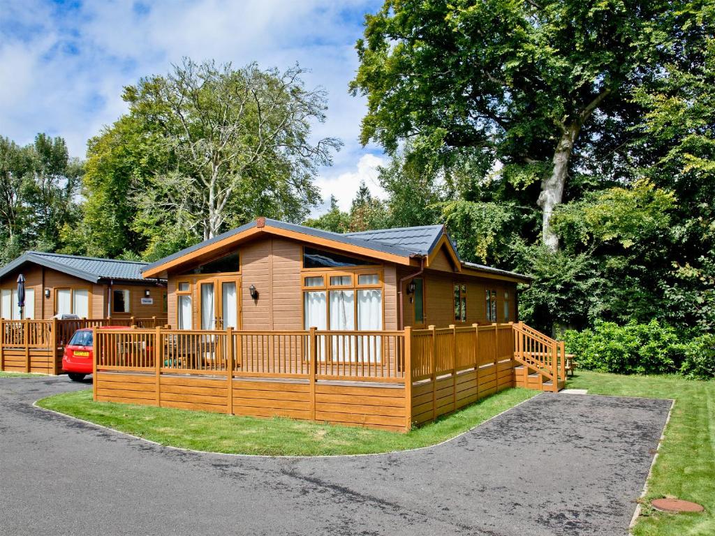 a large wooden cabin with a large deck at Forest Glade Lodge in Lanlivery
