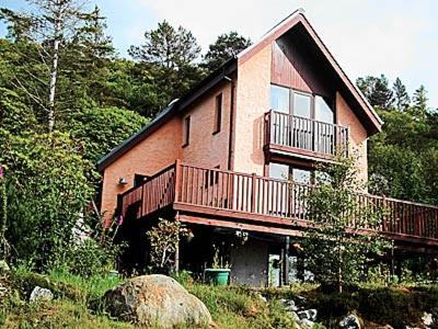 a large brick house with a balcony on the side of it at Waterside Lodge in Port Appin