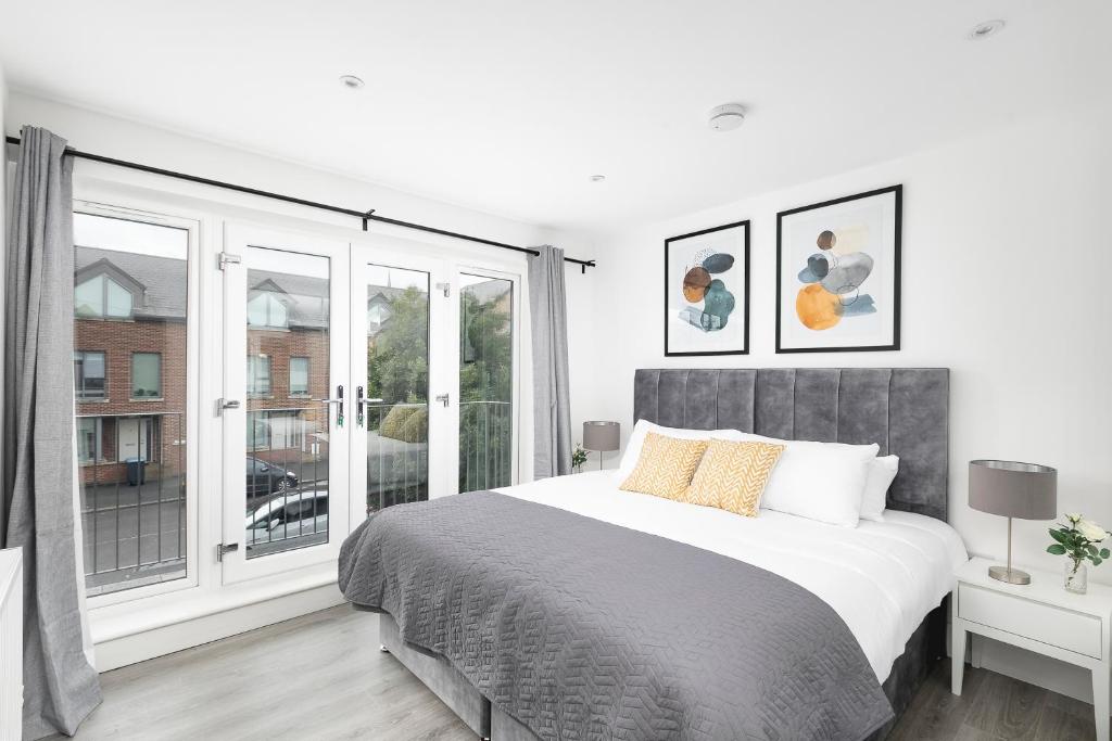 Skyvillion - London Enfield Chase Apartments with Parking & Wifi في انفيلد: غرفة نوم بيضاء مع سرير كبير ونافذة