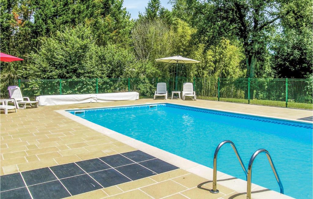 a swimming pool with two chairs and an umbrella at Riverside Retreat in La Barde