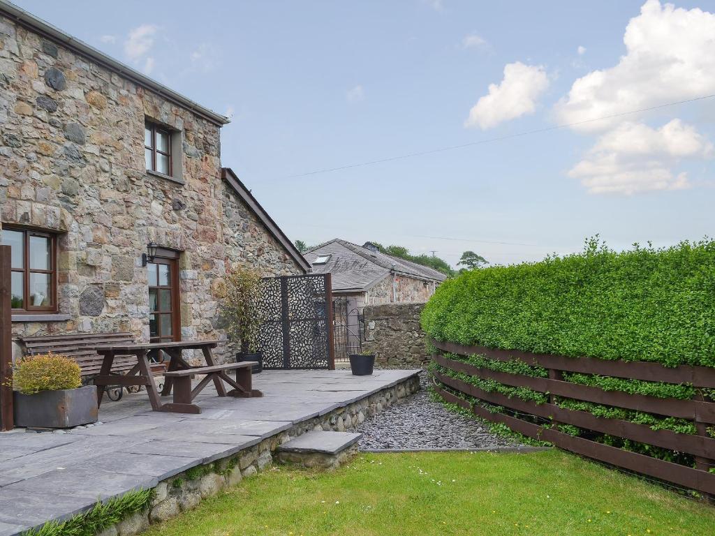 a patio with a picnic table next to a building at Hen Stabl - 16983 in Brynsiencyn