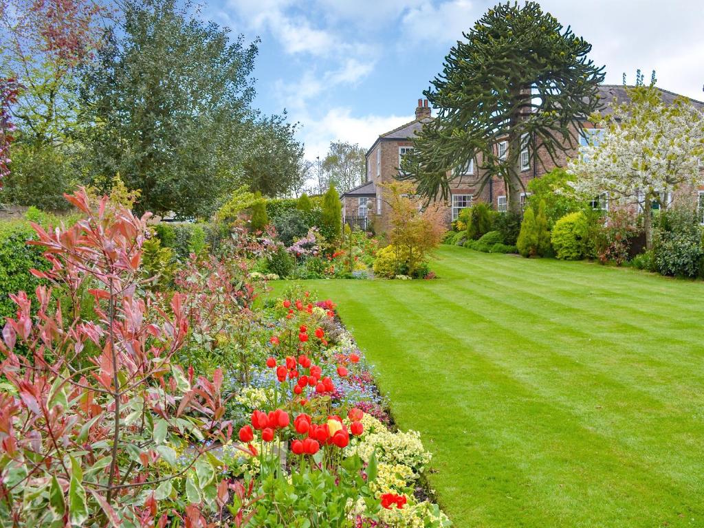 a garden with colorful flowers and a house at Lilac Tree Cottage in Dunnington