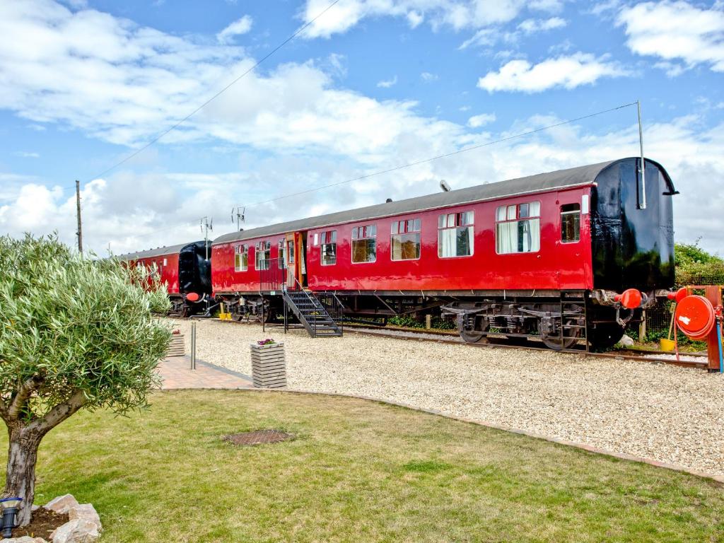 dos vagones de tren rojos sentados en las vías en Brunel Boutique Railway Carriage 4, en Dawlish Warren