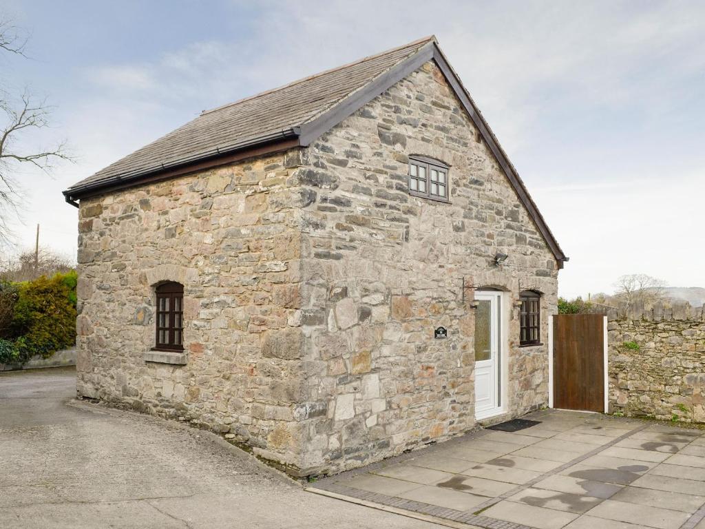 a small stone building with a white door at The Coach House At Old Vicarage Cottage in Bettws-yn-Rhôs