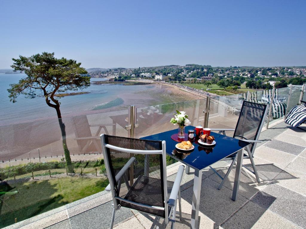 a blue table and chairs with a view of a beach at Riviera Mansion, Torquay in Torquay