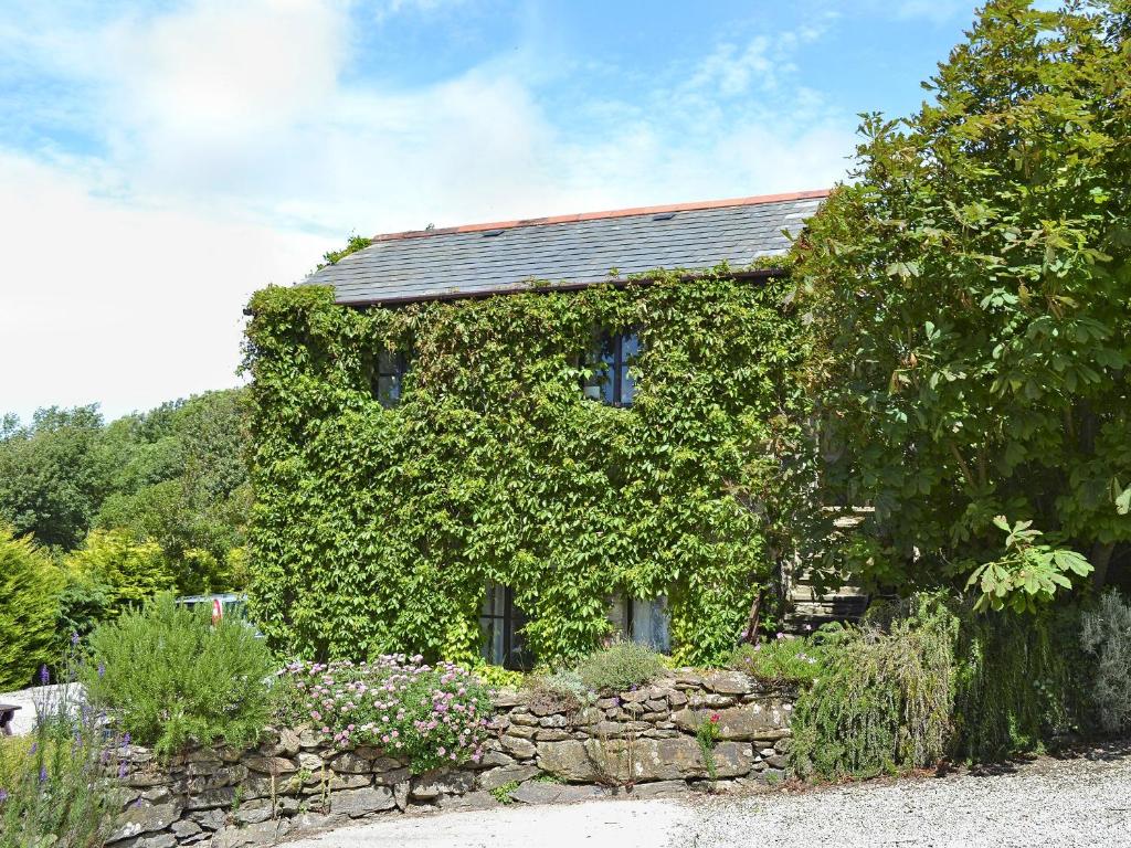an ivy covered house with a stone wall at Hollies Cottage - 27593 in Perranzabuloe