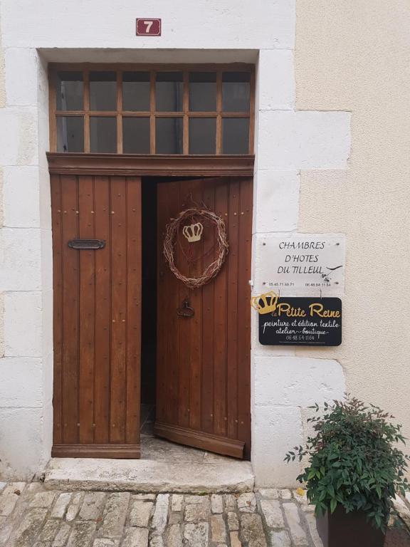 uma porta de madeira com um sinal em frente em chambres d'hôtes du Tilleul em Nanteuil-en-Vallée