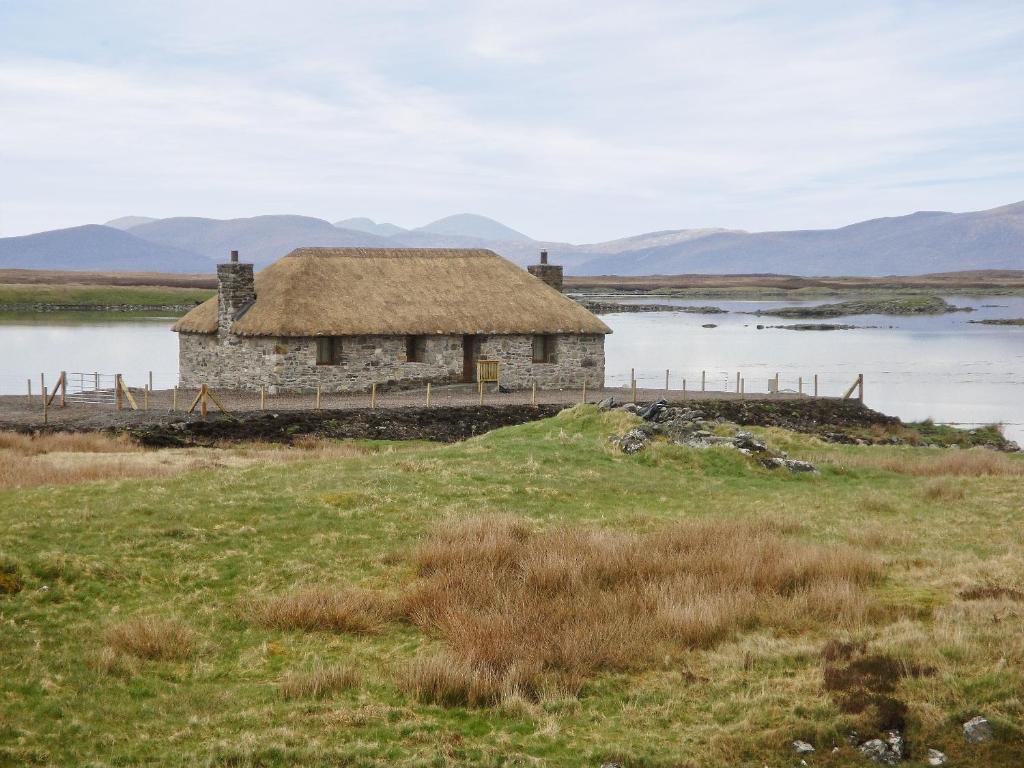 an old house with a grass roof in a field at Creagan Na Mara in Paible