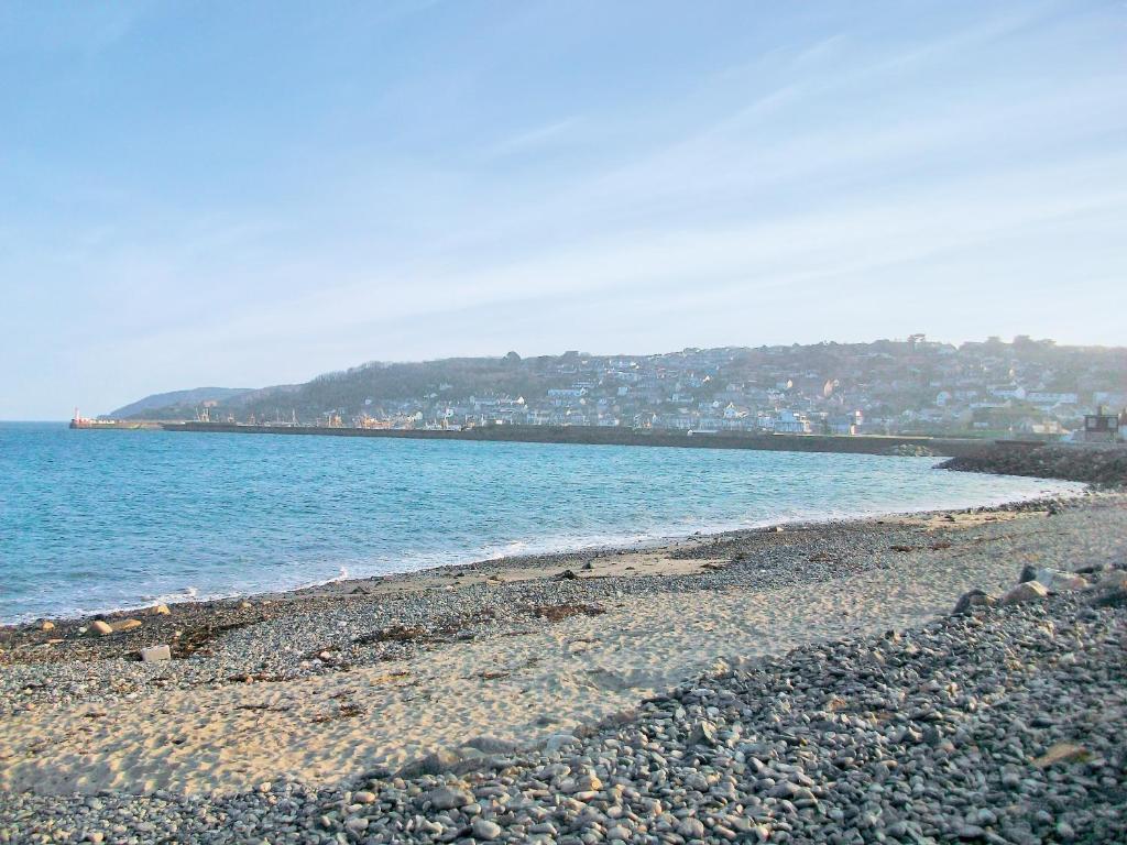 a beach with rocks and water and a city at Salty Cottage in Newlyn