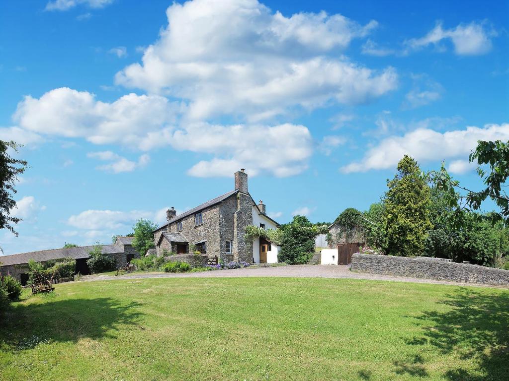 an old stone house with a large grass yard at Boundstone Farmhouse in Littleham