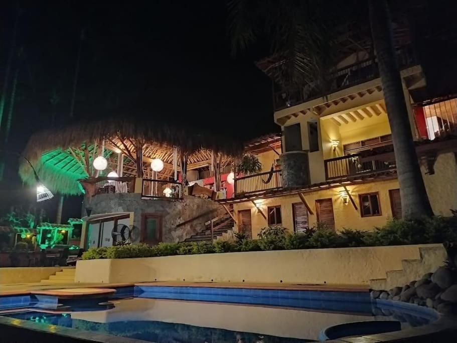ein Hotel mit einem Pool vor einem Gebäude in der Unterkunft Finca Turística La Casa que Canta in Quimbaya