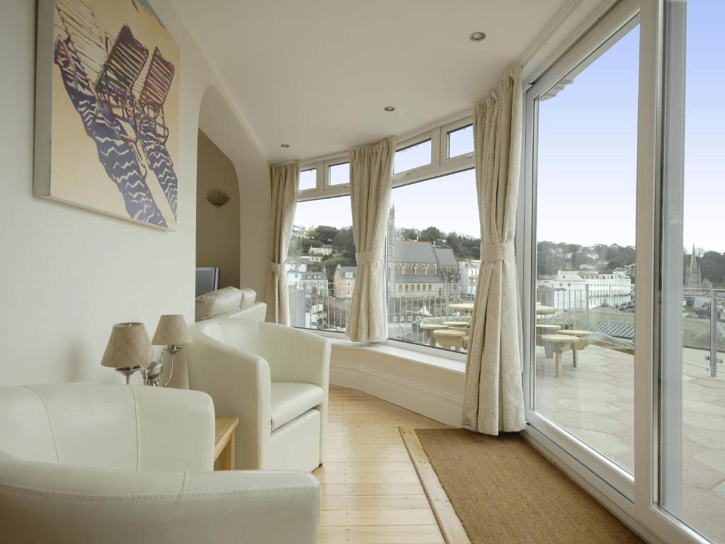 a living room with white furniture and a large window at Rock House in Torquay