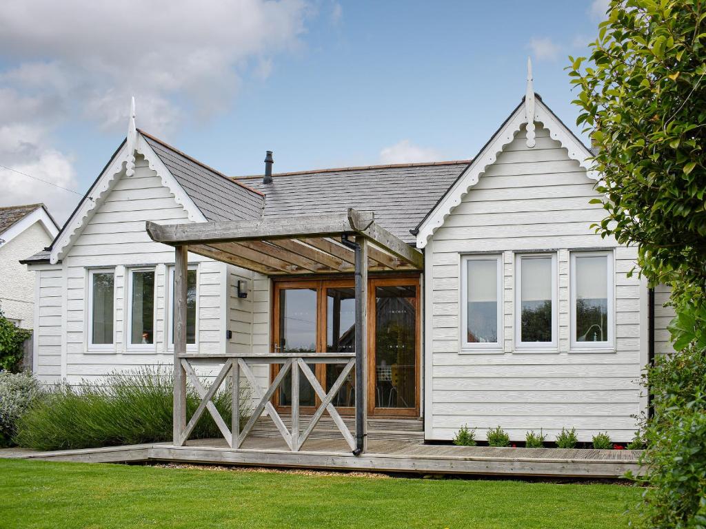 een wit huis met een veranda en een terras bij Mussel Cottage in Middleton-on-Sea