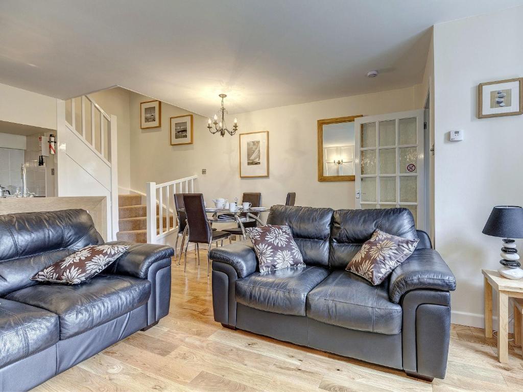 a living room with two leather couches and a dining room at 6 Torwood Gables in Torquay