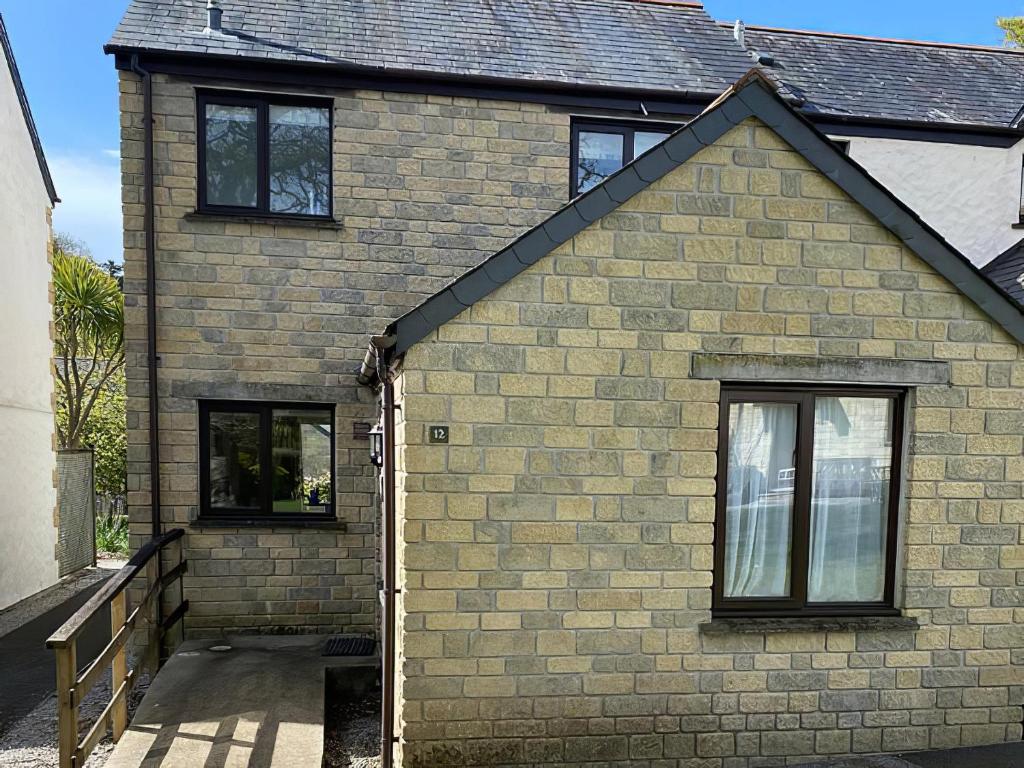 a brick house with two windows and a driveway at Trellee in Budock Water