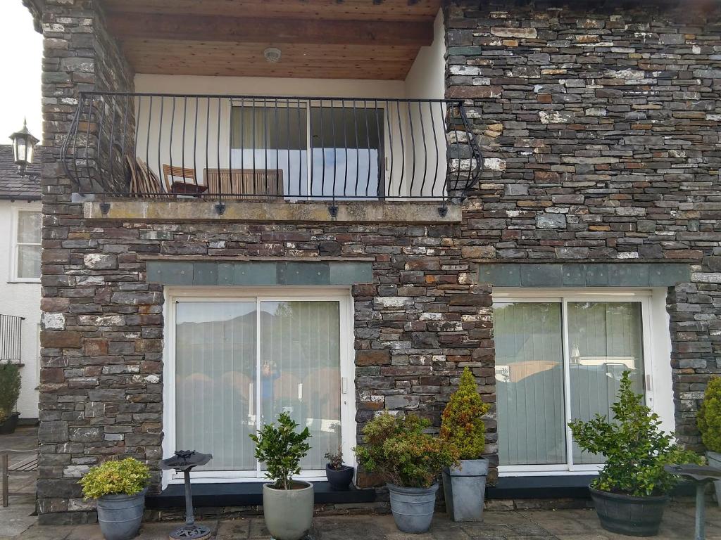 uma casa de tijolos com duas janelas e uma varanda em Derwentwater View em Portinscale