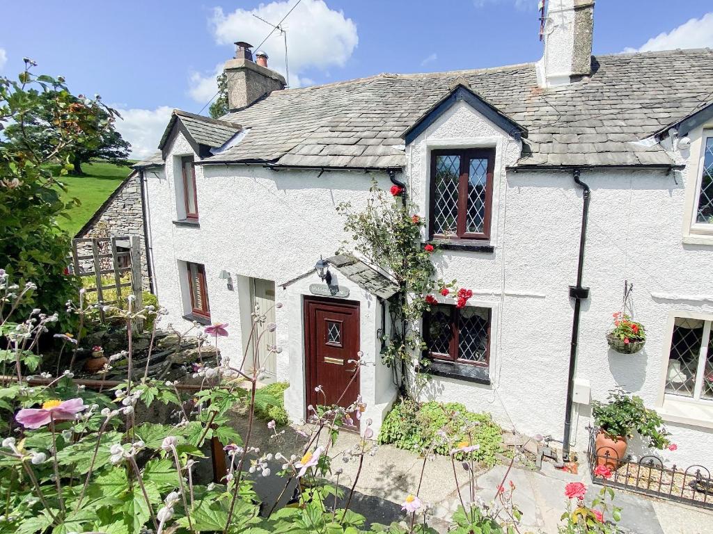 una casa blanca con flores delante en Hidden Cottage en Spark Bridge