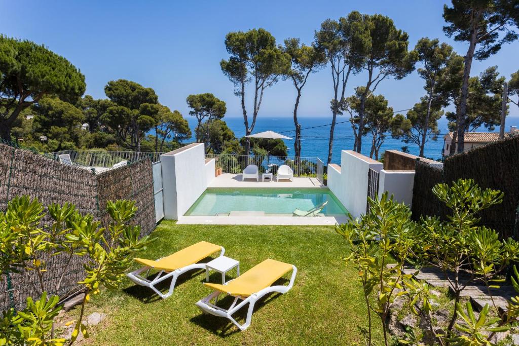 卡萊利亞德帕拉弗魯赫爾的住宿－Luxury Villa in front of the sea PROA，后院设有游泳池和两把椅子