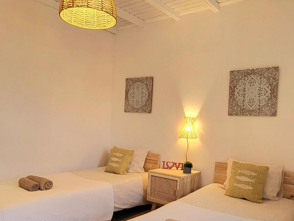 a room with two beds and a table with a lamp at Cantinho de Milfontes Quarto Twin in Vila Nova de Milfontes