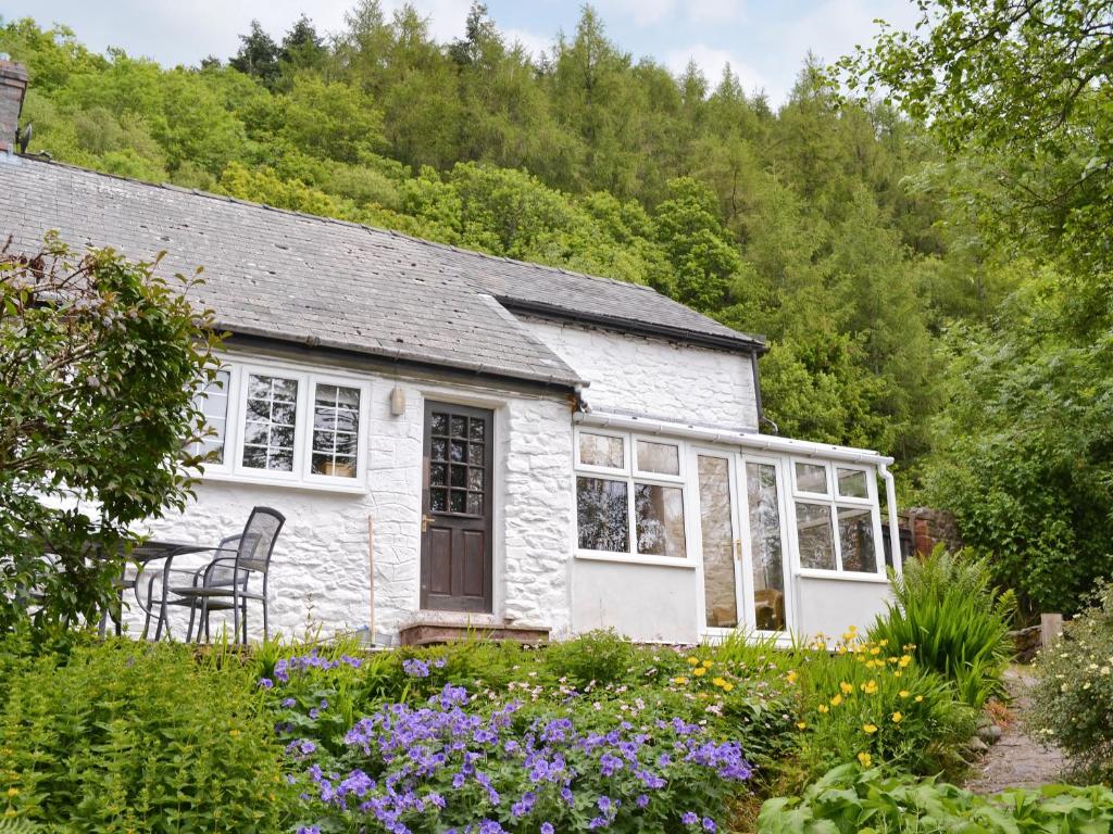 a white cottage with a table and chairs in a garden at The Old Smithy in Llanbadarn-fynydd