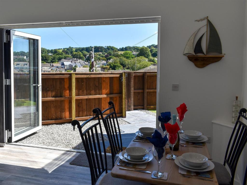 a dining room table with chairs and an open patio door at Apple Barn Cottage in Brixham