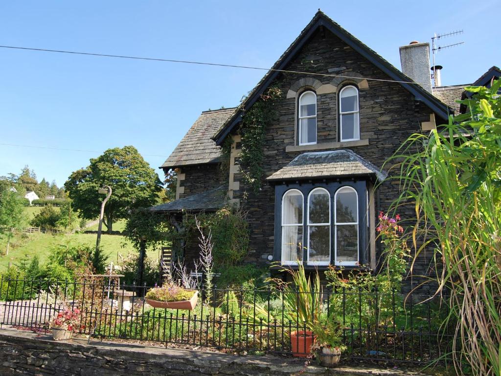 uma casa velha com uma cerca em frente em 1 School Cottage em Troutbeck Bridge