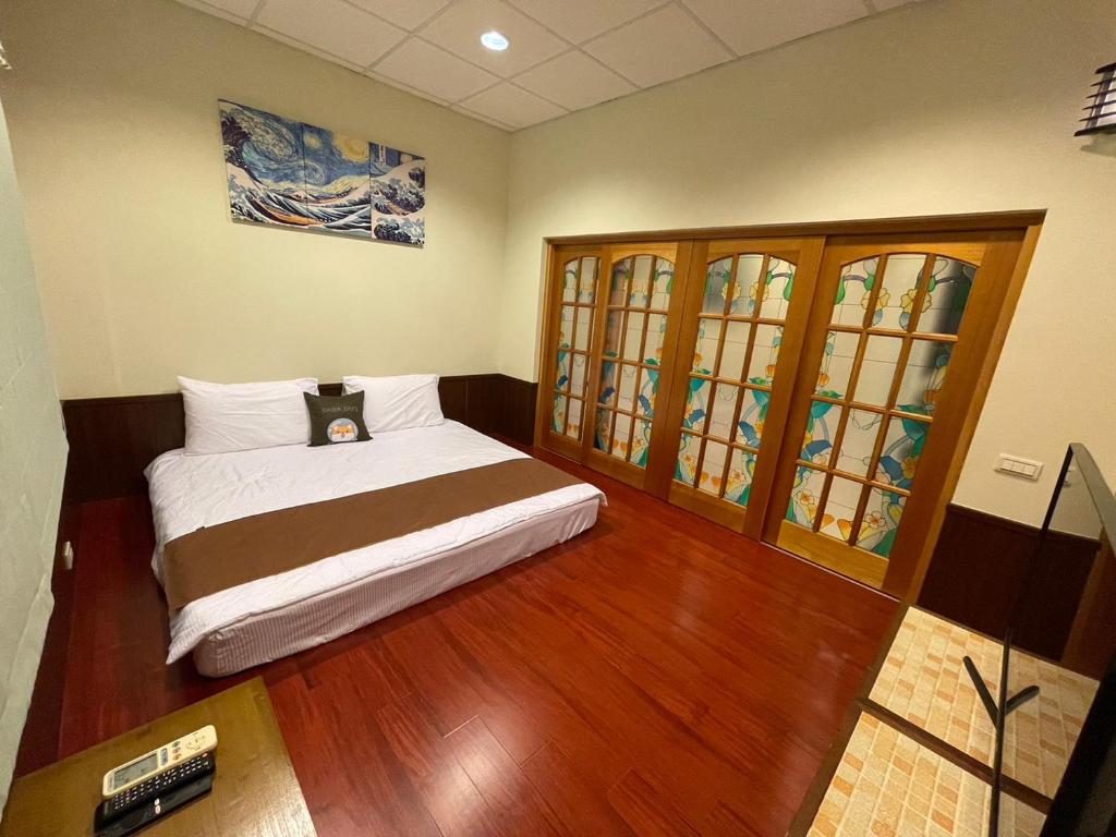 sypialnia z łóżkiem, drewnianą podłogą i oknami w obiekcie Rimin Hostel w mieście Nanxi